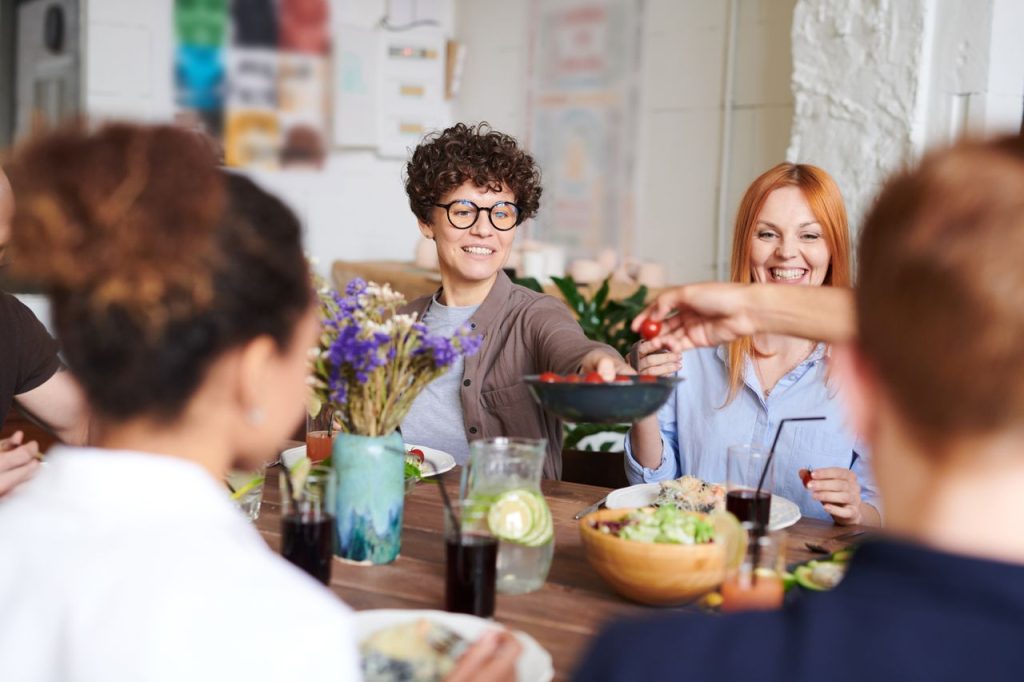 A group of friends gathered around a table, sharing food and smiling. Real longevity medicine is about relationships - with your body, community, and the rhythm of the natural world.
